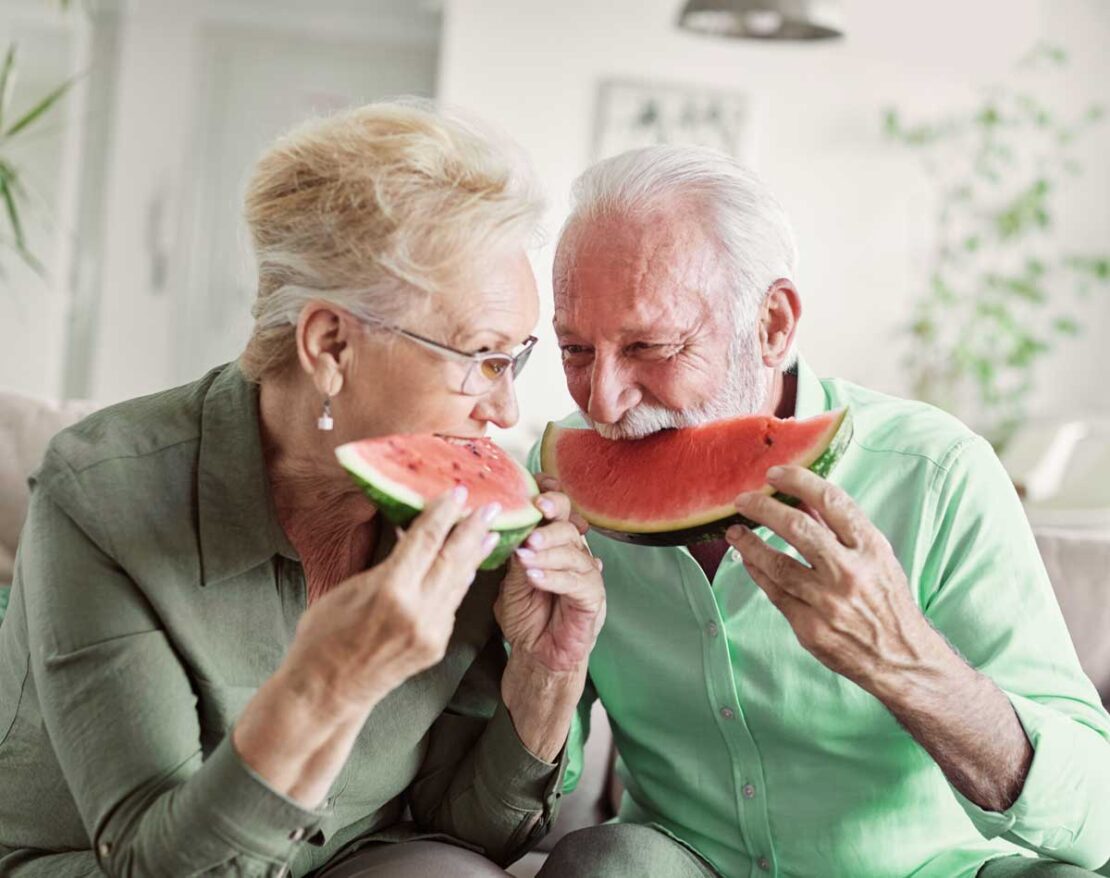 Coppia di anziani mangia anguria. Alimentazione corretta e idratazione sono vitali per la salute degli anziani con il caldo.