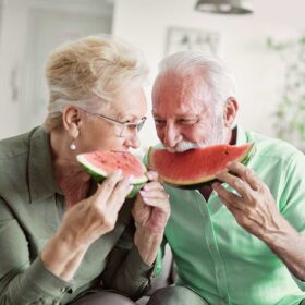 Coppia di anziani mangia anguria. Alimentazione corretta e idratazione sono vitali per la salute degli anziani con il caldo.