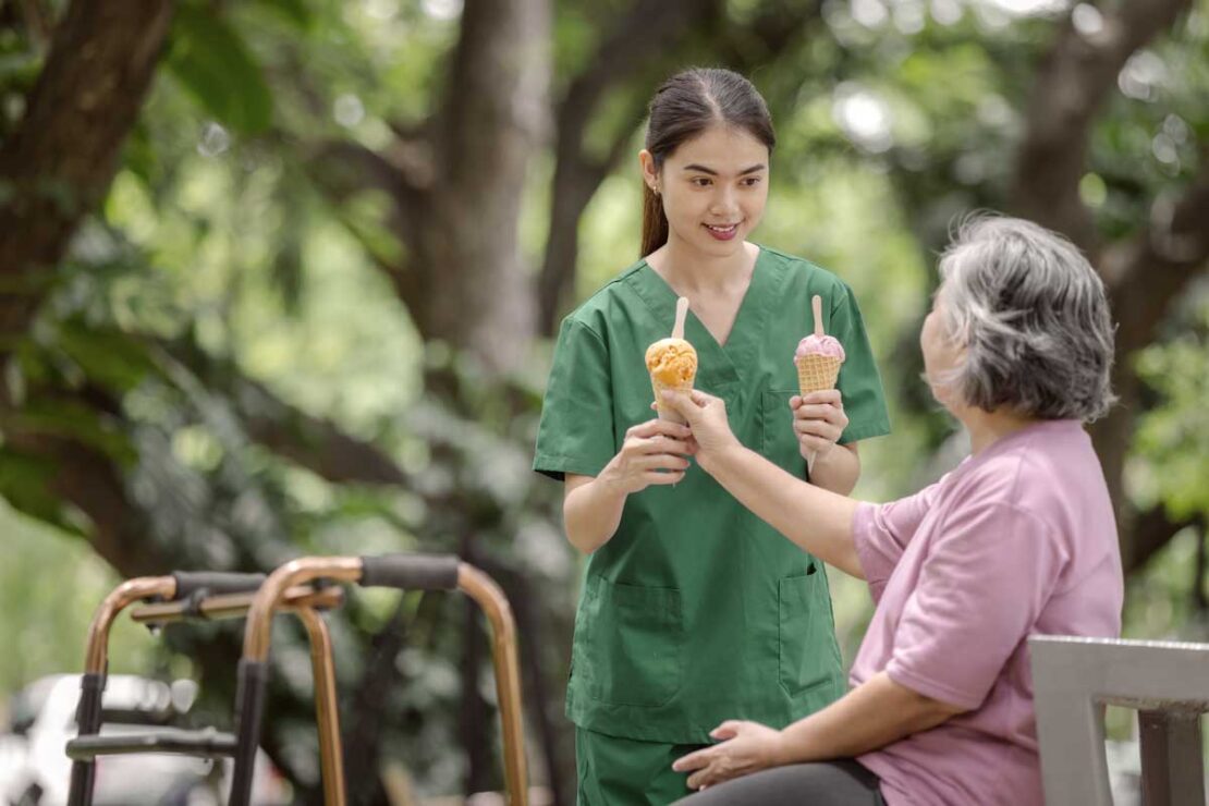 Una OSS offre un gelato a un'anziana. Un modo per idratare e rinfrescare gli anziani e combattere il caldo.